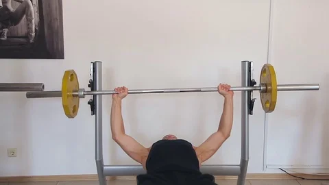 Young man bench pressing weights at a gym Video stock 71597239