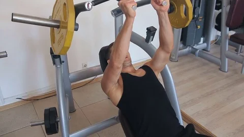 Young man bench pressing weights at a gym Video stock 71602122