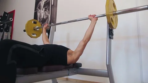 Young man bench pressing weights at a gym Video stock 71602373