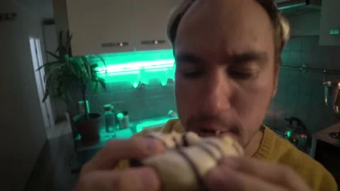 Young man bites fun at the donut in the kitchen Stock Footage 142397961