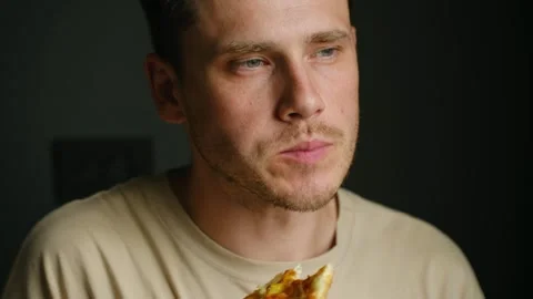 Young man bites off slice of tasty pepperoni pizza at home Stock Footage 282001970