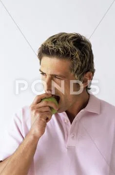 Young man biting apple, close-up Stock Photos