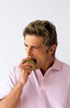 Young man biting apple, close-up Stock Photos