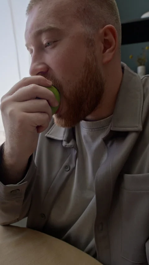 Young Man Biting Green Apple while Working from Home Stock Footage 315868270