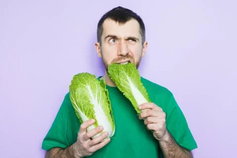Young man biting on a leaf of Beijing napa cabbage Stock Photos