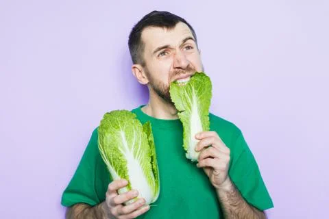 Young man biting on a leaf of Beijing napa cabbage Stock Photos