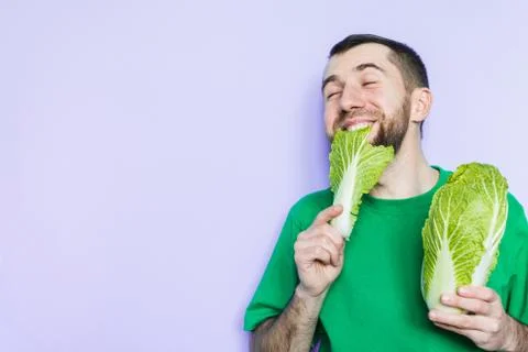 Young man biting on a leaf of Beijing napa cabbage Stock Photos
