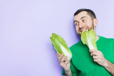 Young man biting on a leaf of Beijing napa cabbage Stock Photos