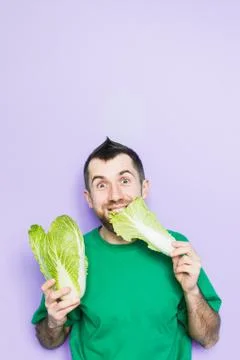 Young man biting on a leaf of Beijing napa cabbage Stock Photos