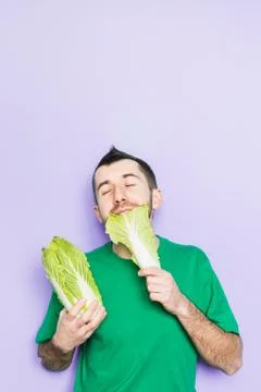 Young man biting on a leaf of Beijing napa cabbage Stock Photos