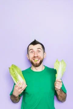 Young man biting on a leaf of Beijing napa cabbage Stock Photos