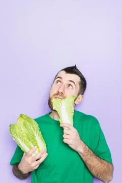 Young man biting on a leaf of Beijing napa cabbage Stock Photos