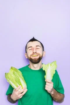Young man biting on a leaf of Beijing napa cabbage Stock Photos