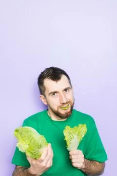 Young man biting on a leaf of Beijing napa cabbage Stock Photos