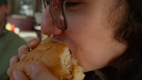 Young Man Biting into Tasty Extra Large Hamburger at Restaurant Stock Footage 335752212