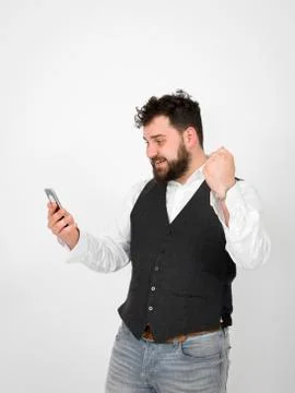 Young man with black beard is posing and looking at his smartphone Foto stock