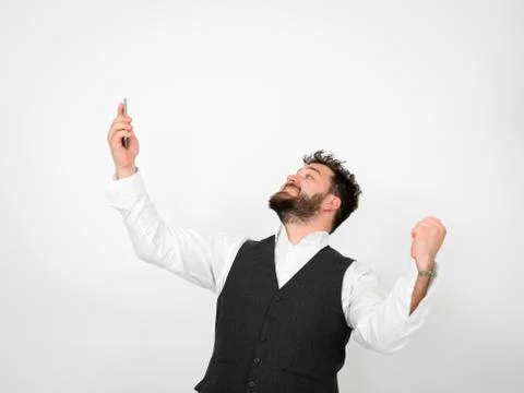Young man with black beard is posing and looking at his smartphone Foto stock