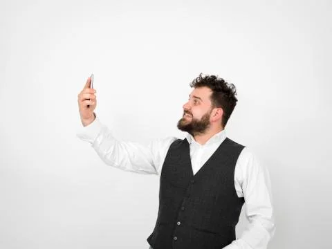 Young man with black beard is posing and looking at his smartphone Stock Photos