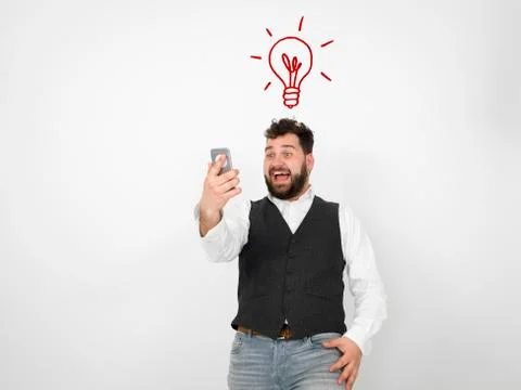 Young man with black beard is posing and looking at his smartphone Stock Photos