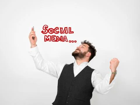 Young man with black beard is posing and looking at his smartphone Stock Photos
