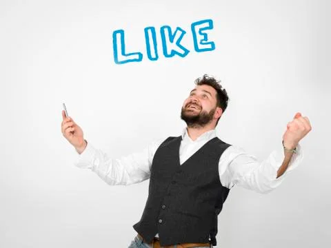 Young man with black beard is posing and looking at his smartphone Stock Photos