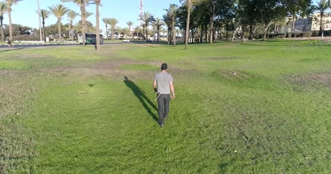 Young man in black cap and protective mask walking through a park. Stock Footage 135203773