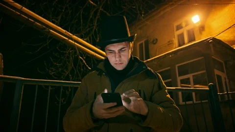 A young man in a black hat uses the phone. Stockbeeldmateriaal 102137991