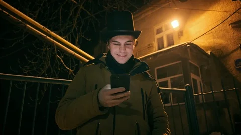 A young man in a black hat uses the phone. Shows emotions 動画素材 102138291