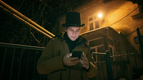 A young man in a black hat uses the phone. Shows emotions 動画素材 102138509