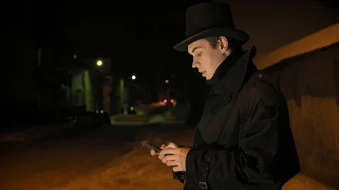 A young man in a black hat uses the phone. Shows emotions Vídeos de archivo 103365216