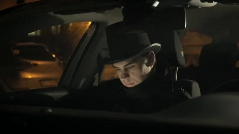 A young man in a black hat uses the phone in car. 4k Stockbeeldmateriaal 103367859