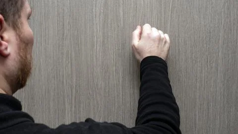 A young man in a black jacket knocks on the door. Visiting someone's home Stock Photos