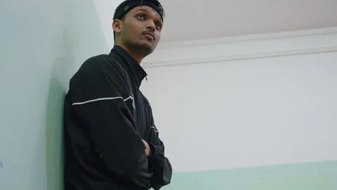 Young Man in Black Jacket Leaning Against Wall Indoors Stock Footage 319202882