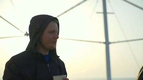 Young man in black jacket standing on the pier drinking coffee Video stock 75586544