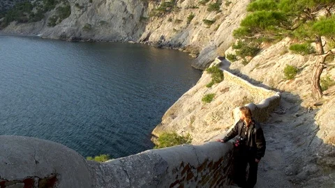 Young man in black jacket stands in front of stone fence of Galitsyn trail. Stock Footage 107133032