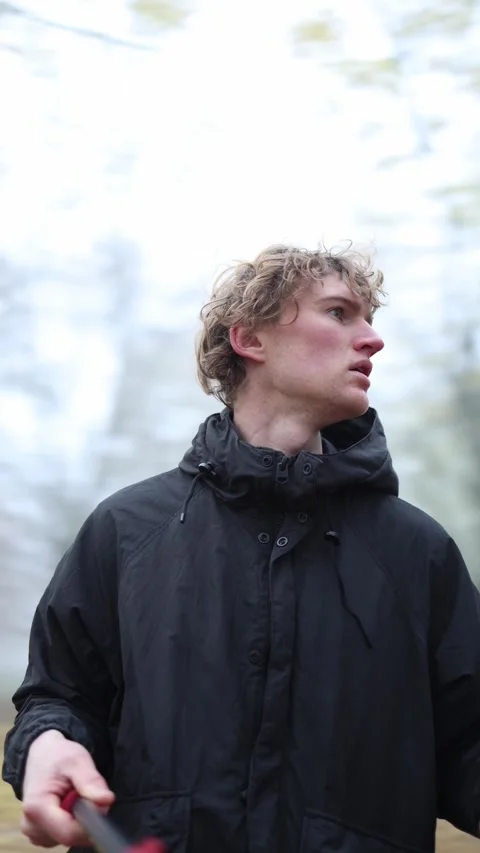 A young man in a black jacket stands outdoors, looking off to the side with a pe Stock Footage 290187344