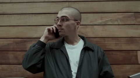 Young man in black jacket talking on the phone Video stock 258271438