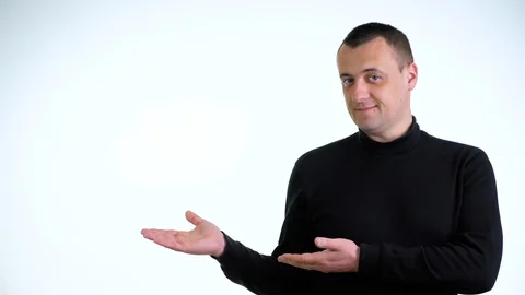 Young man in black sweater pointing rightwards against white background. Stock Footage 129548657