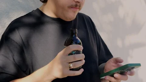 Young man in black t‑shirt drinking from bottled coffee while... Stock Footage 323327949