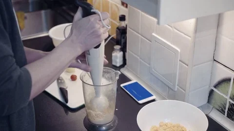 Young man blender preparing vegetable food at home kitchen and watching video Stock Footage 74157652