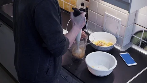 Young man with blender preparing vegetable meal at home kitchen and smartphone Stock Footage 74158998