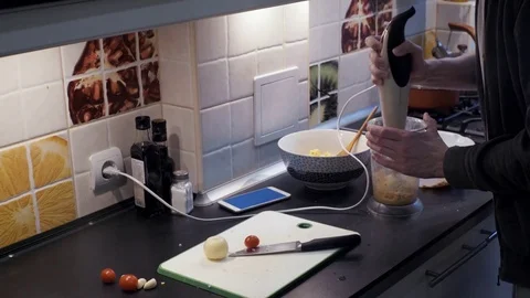 Young man with blender preparing vegetable meal at home kitchen and smartphone Video stock 74159647
