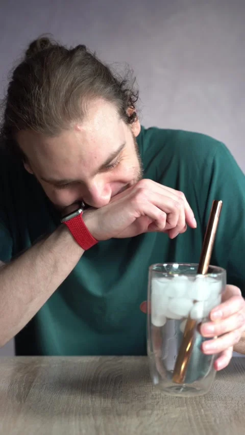 Young man blowing bubbles in ice water, spilling and laughing Stock Footage 229650955