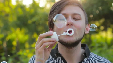 Young man blowing soap bubbles Stock Footage 98136824