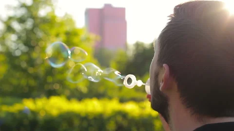 Young man blowing soap bubbles, back view Stock Footage 103538727