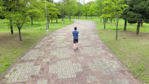 A young man in blue clothes running in park rear view. Stock Footage 135108235
