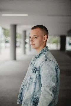A young man in a blue denim jacket stands in a hallway Foto stock