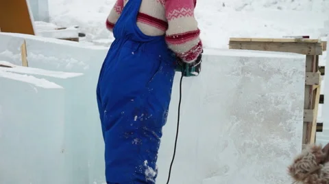 Young man in blue working suit cutting ice with saw Stock Footage 40809183