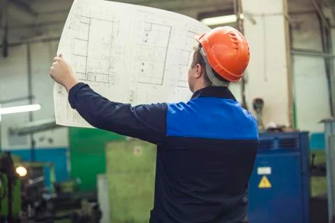 Young man with blueprints working on an old factory for the installation of e Stock Photos