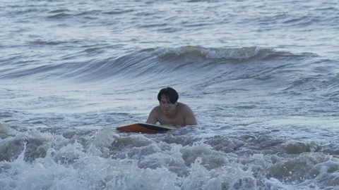 Young Man Bodyboarding Through Breaking Ocean Waves Near Sandy Beach 스톡 동영상 337954685